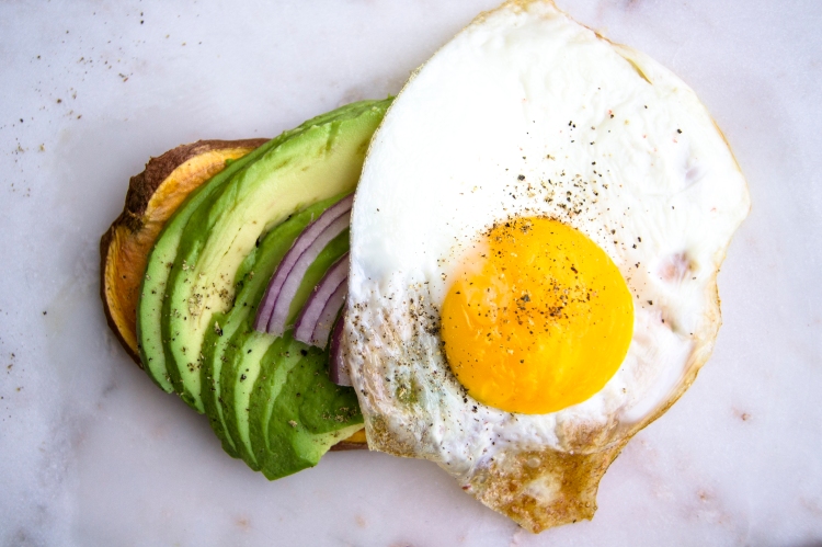 sweet potato toast with avocado, red onion, and egg toppings